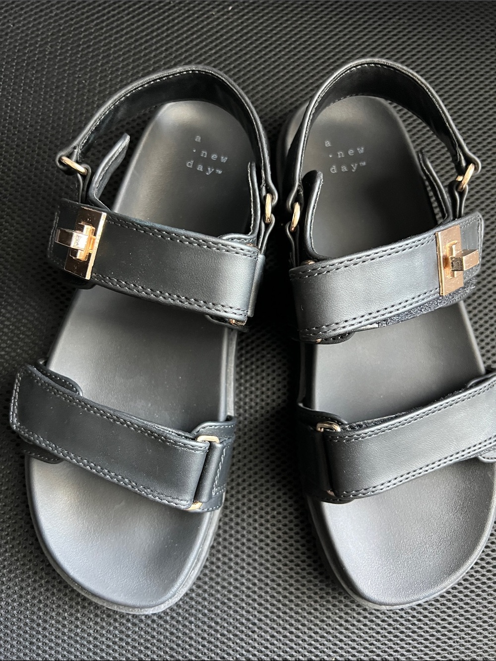 a new day Woman’s Size 8 Black Velcro strap sandals with gold hardware.